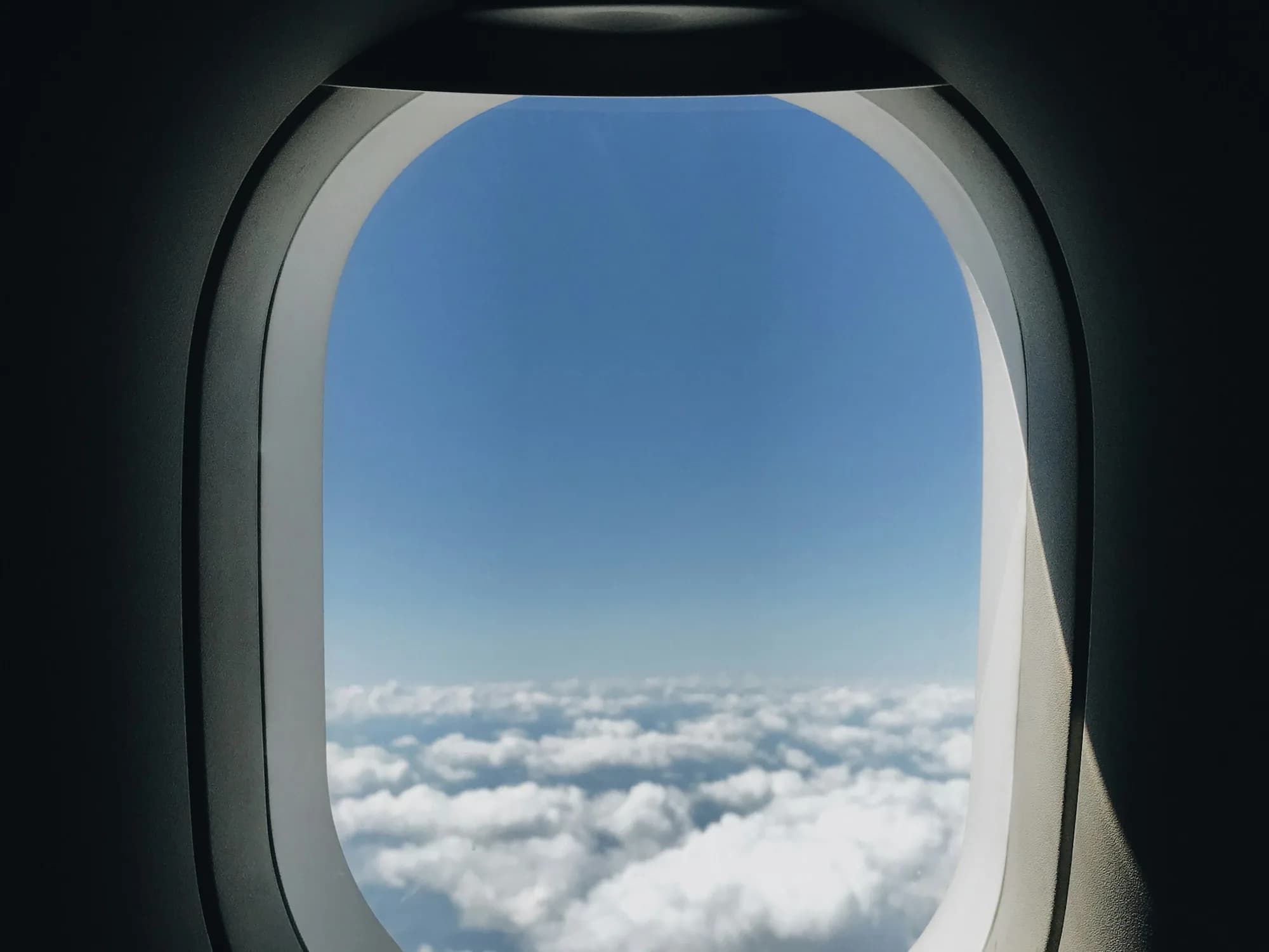 View of blue sky and clouds through an airplane window